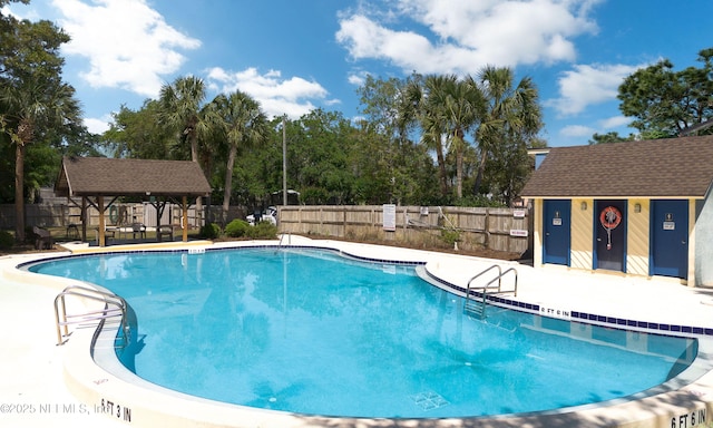 pool featuring a gazebo, a patio area, an outbuilding, and fence