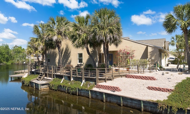 back of house featuring stucco siding and a water view