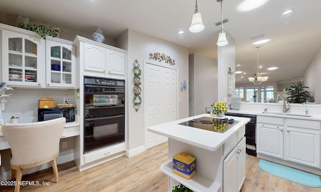 kitchen featuring white cabinets, light wood finished floors, visible vents, a sink, and black appliances