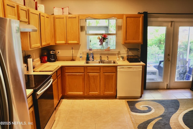 kitchen with a sink, light tile patterned flooring, plenty of natural light, light countertops, and appliances with stainless steel finishes
