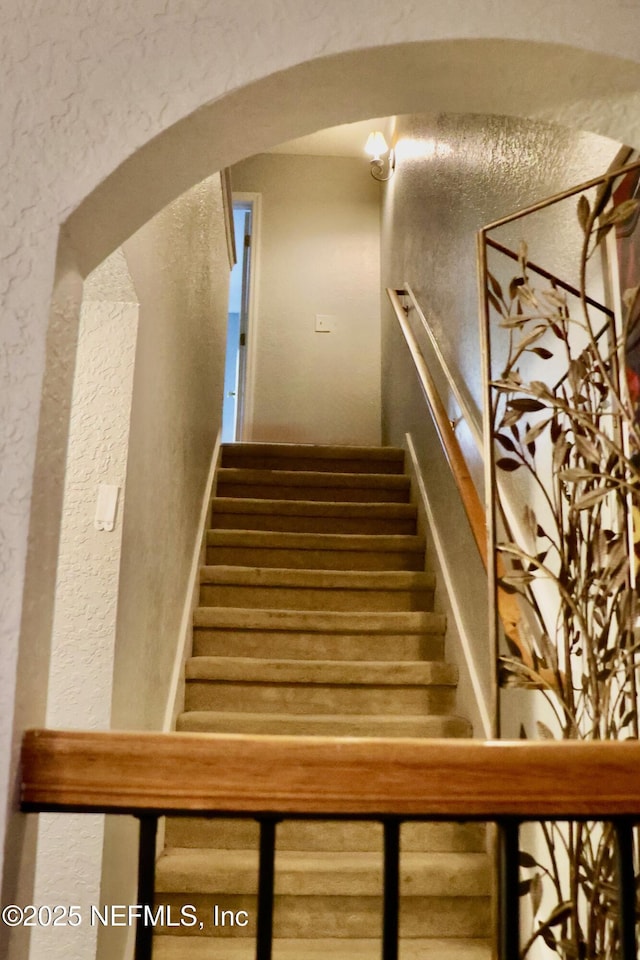 stairs featuring a textured wall and arched walkways