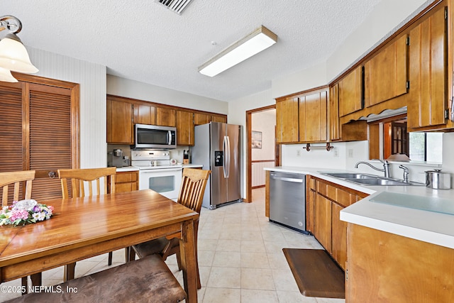 2629 Sandlewood Cir, Orange Park, FL 32065 - kitchen with a sink, stainless steel appliances, brown cabinetry, visible vents, and light countertops