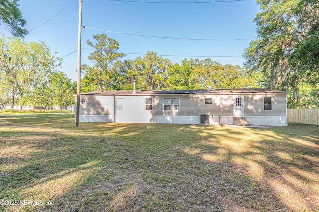 back of property featuring fence, a lawn, entry steps, and central AC unit