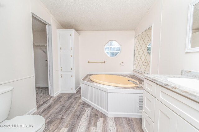 full bathroom with a bath, toilet, vanity, and a textured ceiling