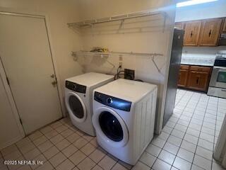 washroom with light tile patterned floors, washing machine and clothes dryer, and laundry area