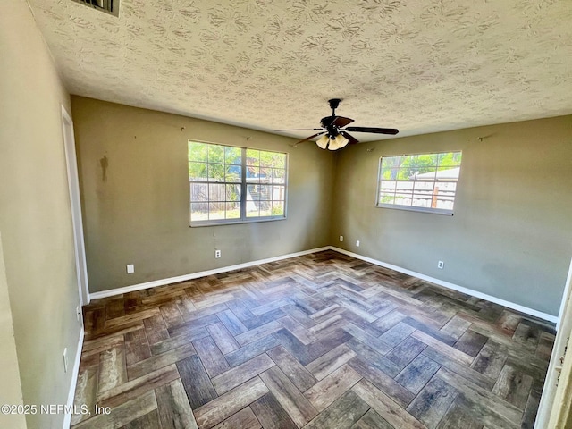 unfurnished room featuring baseboards, ceiling fan, a textured ceiling, and a wealth of natural light