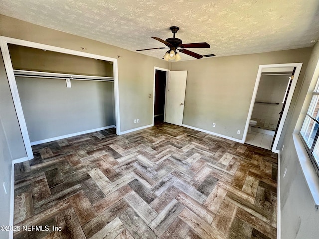 unfurnished bedroom featuring a textured ceiling, ceiling fan, ensuite bathroom, baseboards, and a closet