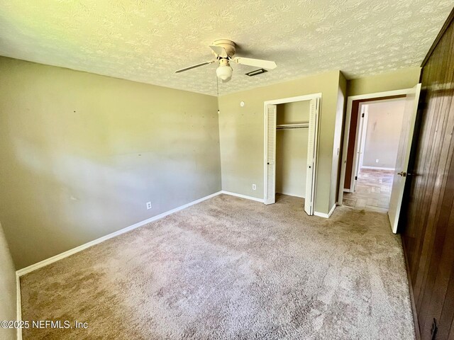 unfurnished bedroom with carpet flooring, a closet, a ceiling fan, baseboards, and a textured ceiling