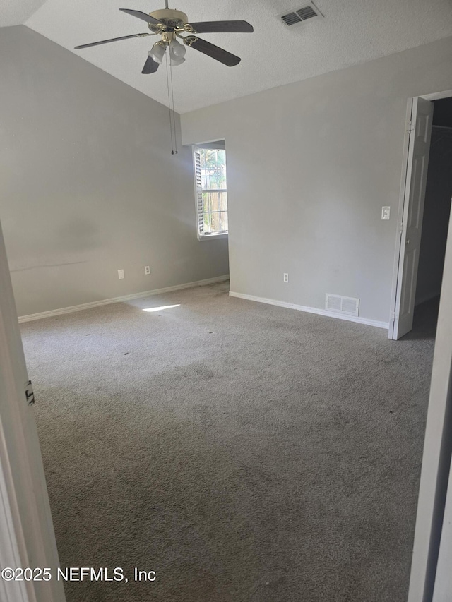empty room with baseboards, a ceiling fan, visible vents, and vaulted ceiling