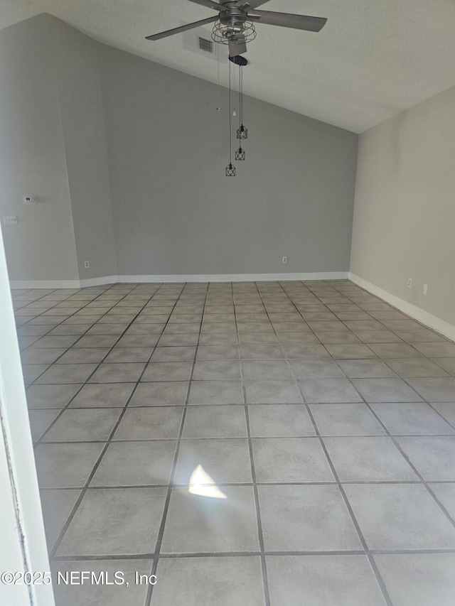 spare room featuring light tile patterned flooring, vaulted ceiling, visible vents, and a ceiling fan