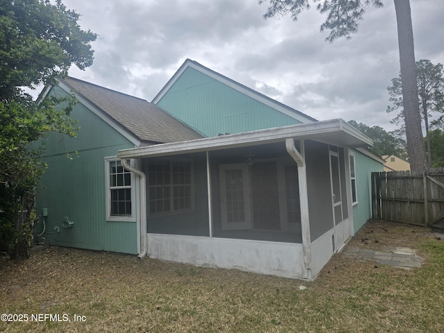 view of side of home with a sunroom and fence