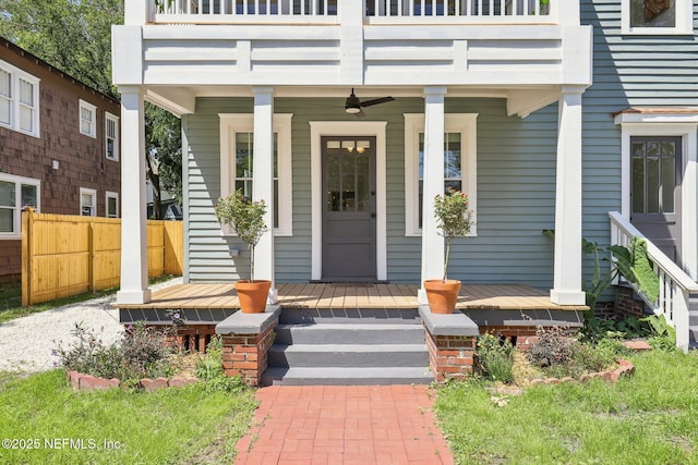 entrance to property with a porch, a balcony, and fence
