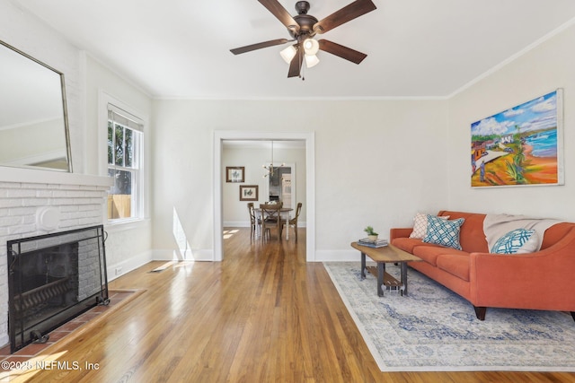 living area with wood finished floors, a brick fireplace, a ceiling fan, and baseboards