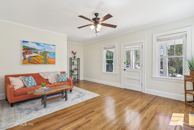 living area with crown molding, baseboards, a ceiling fan, and wood finished floors
