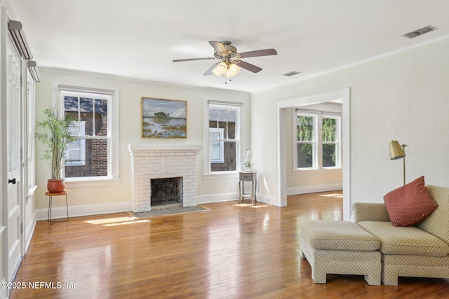living room featuring ceiling fan, baseboards, wood finished floors, and visible vents