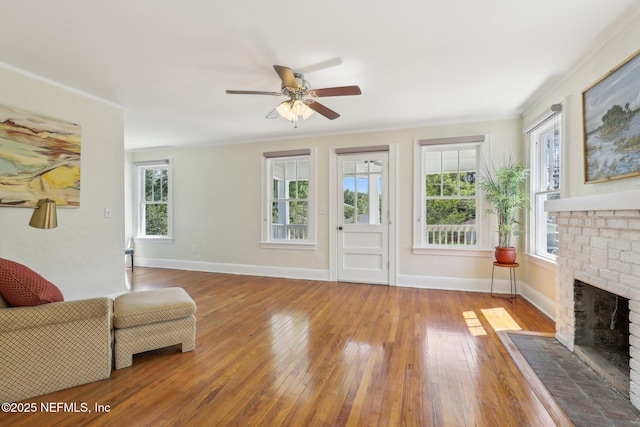 living room with a healthy amount of sunlight, a fireplace, ceiling fan, and wood-type flooring