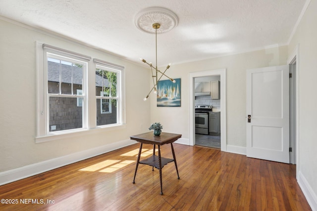 dining room featuring wood finished floors, a textured ceiling, crown molding, and baseboards
