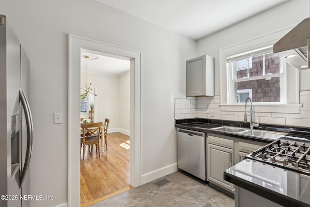 kitchen featuring stainless steel appliances, visible vents, a sink, tasteful backsplash, and a notable chandelier