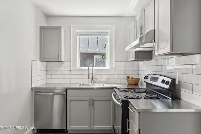 kitchen featuring stainless steel countertops, under cabinet range hood, gray cabinets, and appliances with stainless steel finishes