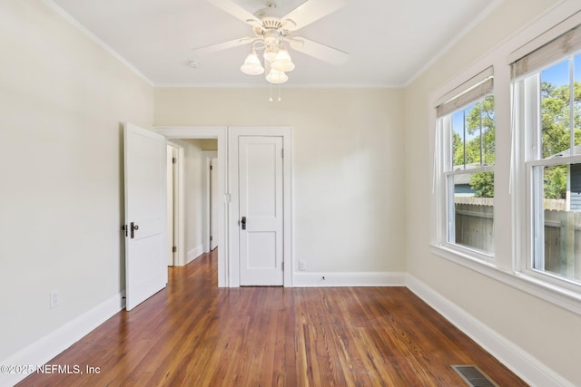spare room featuring wood-type flooring, baseboards, crown molding, and visible vents