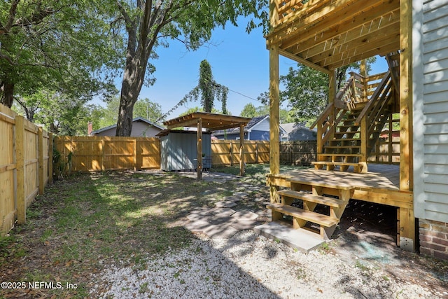 view of yard featuring stairway, a wooden deck, a fenced backyard, and a storage shed