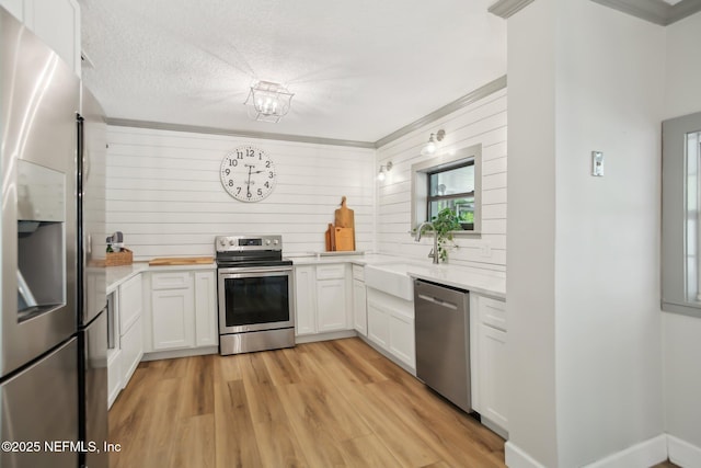 4068 Scenic Dr, Middleburg, FL 32068 - kitchen featuring a textured ceiling, a sink, light wood-style floors, white cabinets, and appliances with stainless steel finishes