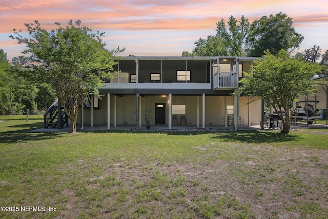 4068 Scenic Dr, Middleburg, FL 32068 - back of property at dusk with a yard, a sunroom, a patio, and stucco siding