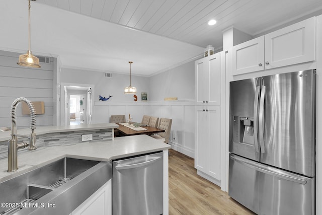 kitchen with white cabinets, stainless steel appliances, ornamental molding, and a sink