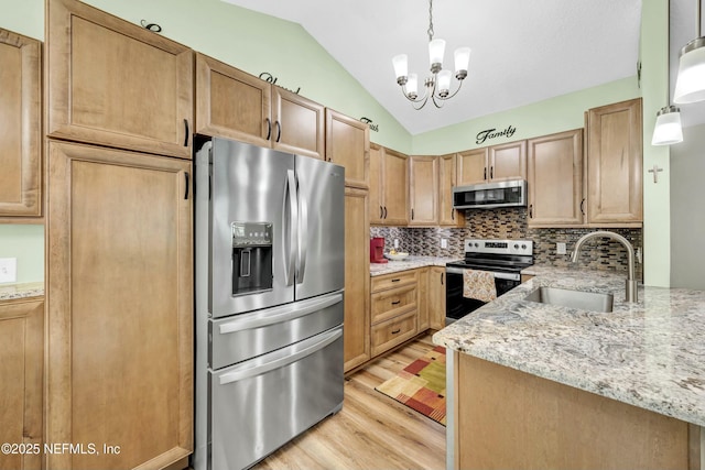 2925 Bradford St, Saint Augustine, FL 32084 - kitchen featuring stainless steel appliances, a sink, light wood-type flooring, vaulted ceiling, and an inviting chandelier