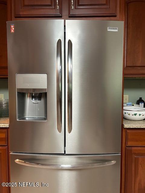 12186 Dividing Oaks Trl W, Jacksonville, FL 32223 - kitchen view of stainless steel refrigerator with ice dispenser, brown cabinetry, and light stone counters
