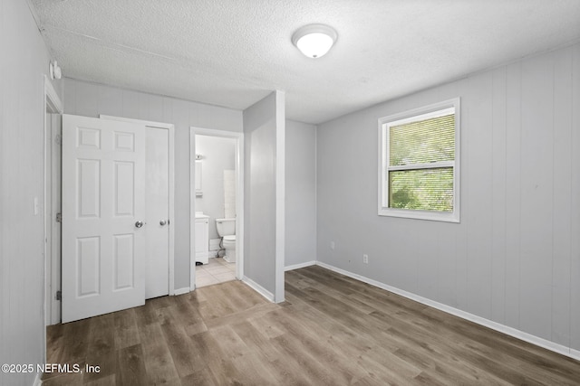 1585 W 31st St, Jacksonville, FL 32209 - unfurnished bedroom with baseboards, wood finished floors, a textured ceiling, and ensuite bathroom