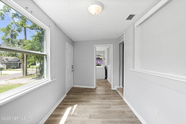 1585 W 31st St, Jacksonville, FL 32209 - corridor featuring light wood-type flooring, a textured ceiling, visible vents, and plenty of natural light