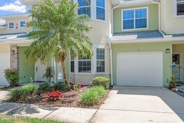 view of exterior entry with stucco siding, an attached garage, and driveway