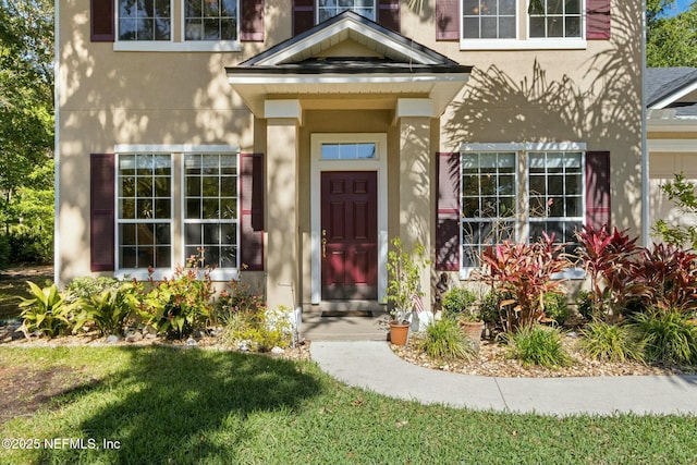 entrance to property with a yard and stucco siding