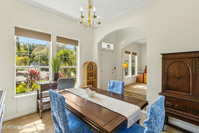 dining space with light carpet, arched walkways, baseboards, a chandelier, and ornamental molding