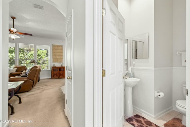 ensuite bathroom with visible vents, toilet, ensuite bath, a textured ceiling, and ceiling fan
