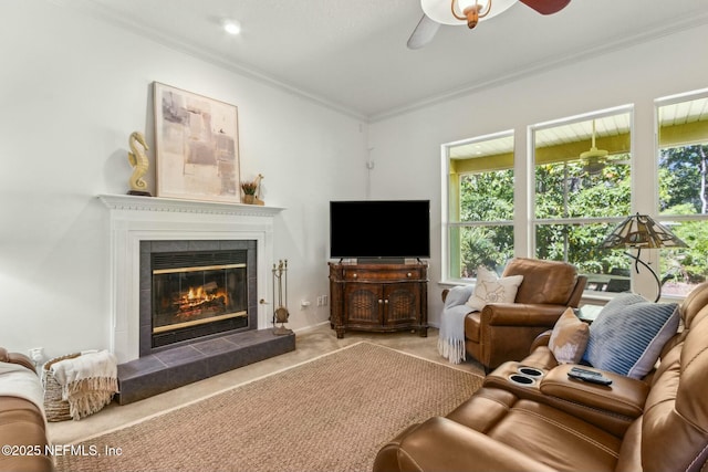 living room featuring a tiled fireplace, a healthy amount of sunlight, a ceiling fan, and ornamental molding