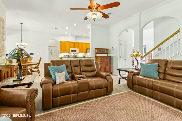 living area with light carpet, arched walkways, visible vents, ceiling fan with notable chandelier, and stairs