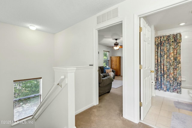 hallway with carpet floors, tile patterned floors, an upstairs landing, and visible vents