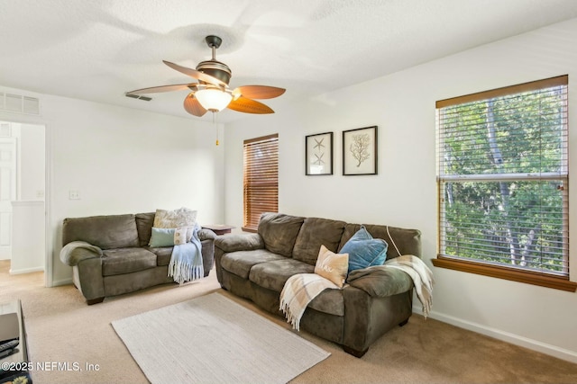 living room featuring light carpet, a ceiling fan, visible vents, and a healthy amount of sunlight