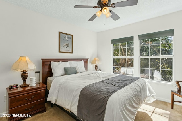 carpeted bedroom with a textured ceiling, a ceiling fan, and baseboards