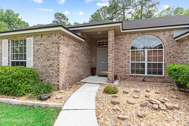 view of exterior entry featuring brick siding