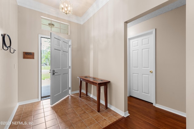 entryway featuring an inviting chandelier, baseboards, and ornamental molding