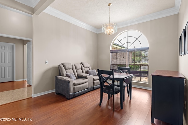 dining room featuring a textured ceiling, crown molding, wood finished floors, baseboards, and a notable chandelier