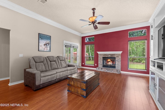 living area with crown molding, a ceiling fan, a textured ceiling, and wood finished floors
