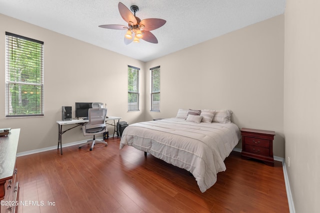 bedroom featuring baseboards, wood finished floors, and multiple windows