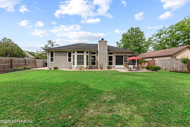 back of property featuring a fenced backyard, a chimney, a yard, and a patio area