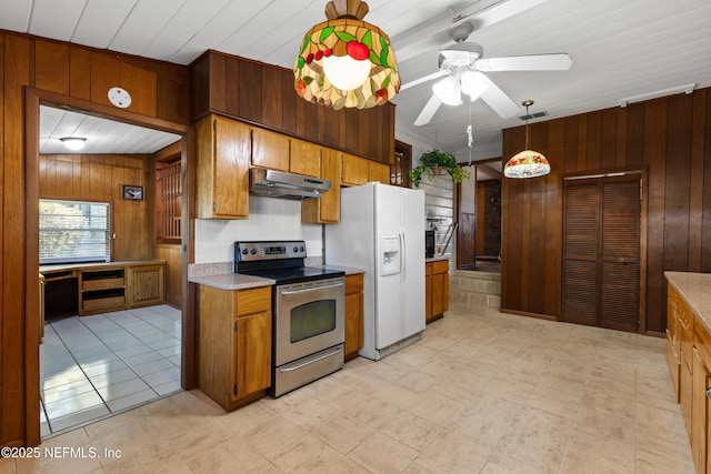 kitchen with stainless steel electric stove, wooden walls, under cabinet range hood, and white fridge with ice dispenser