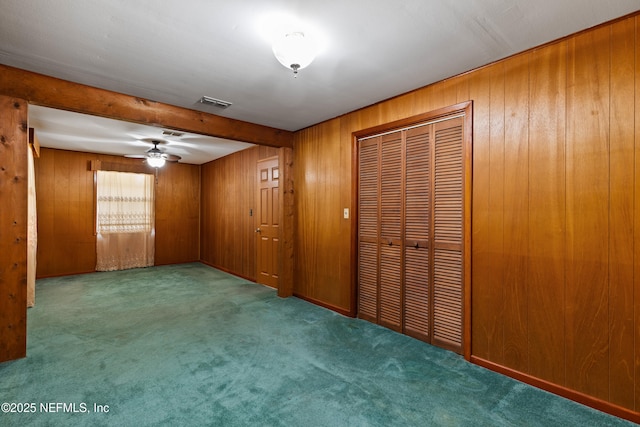 unfurnished bedroom featuring beam ceiling, wooden walls, visible vents, and carpet