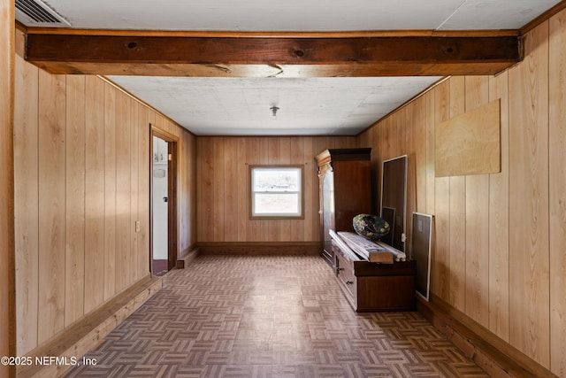 unfurnished room with visible vents, baseboards, and wood walls